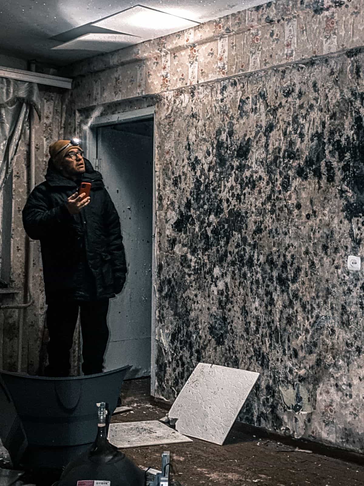 Inspecting mold growth on a wall left by untreated moisture