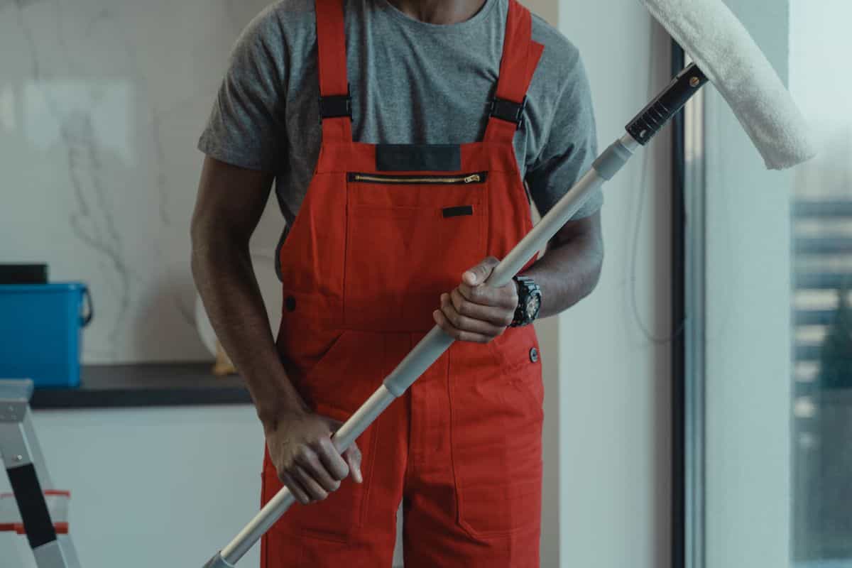 A technician in protective coveralls removing sealed disposal bags from a stripped bathroom