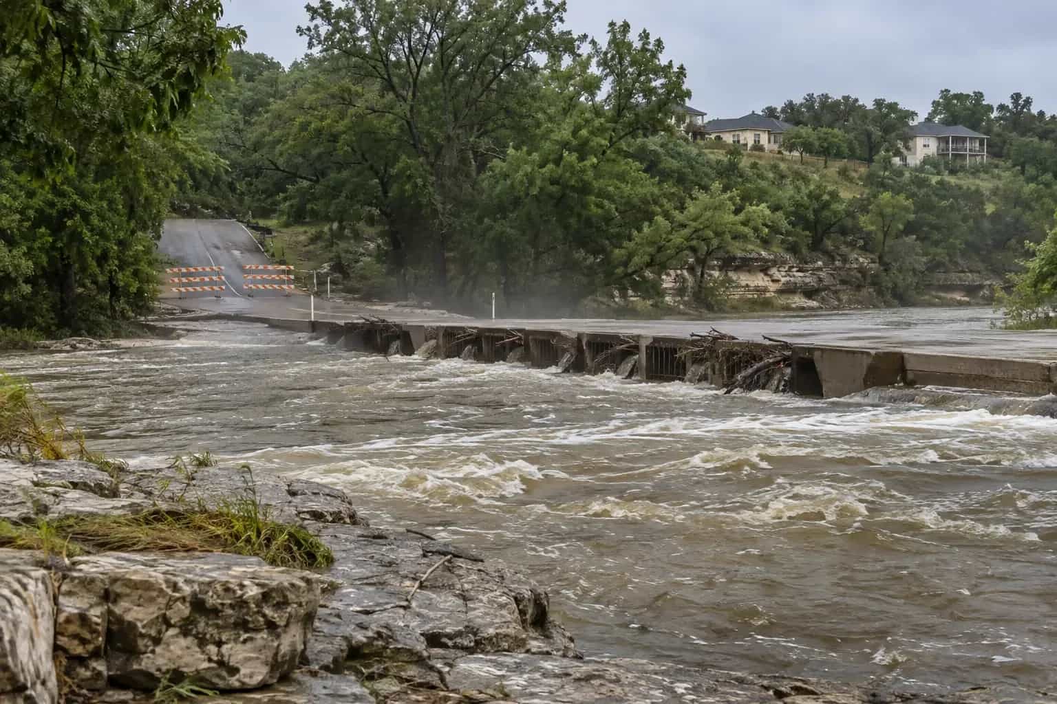 Onion Creek running high past a low-water crossing near homes in Buda, TX after heavy rain