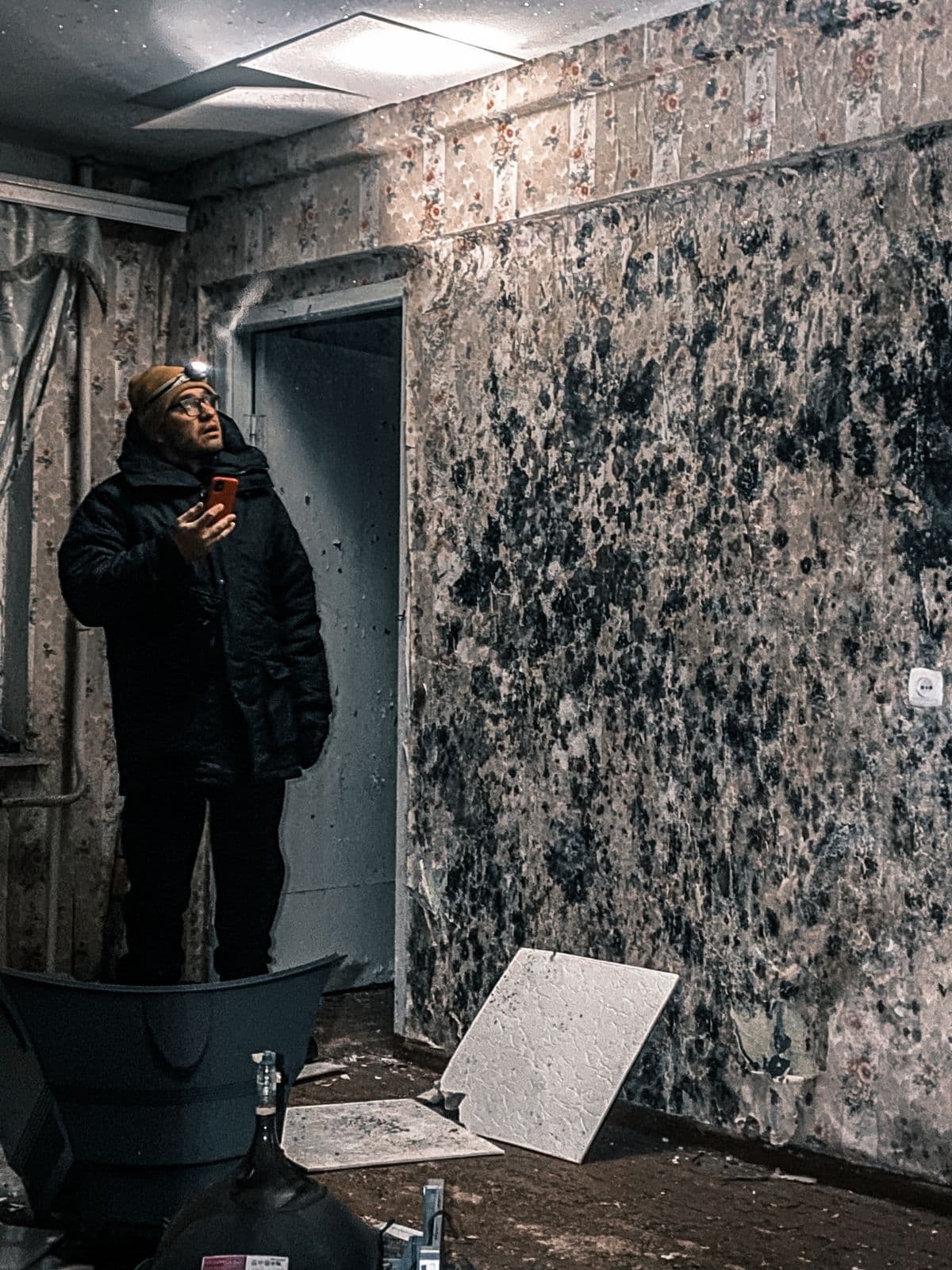 Inspecting mold growth on a wall left by untreated moisture