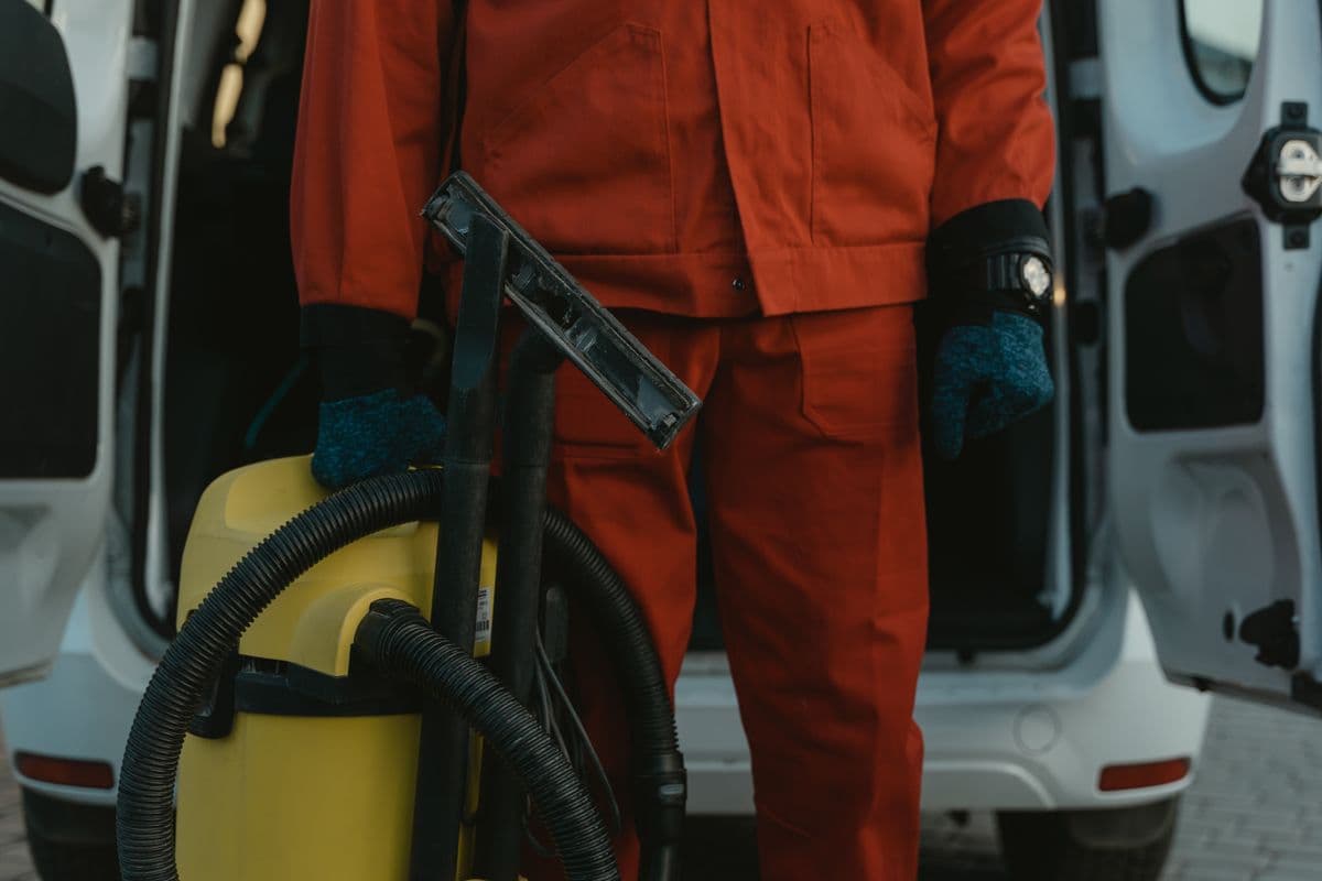 A restoration technician with equipment beside a service van at a San Marcos home