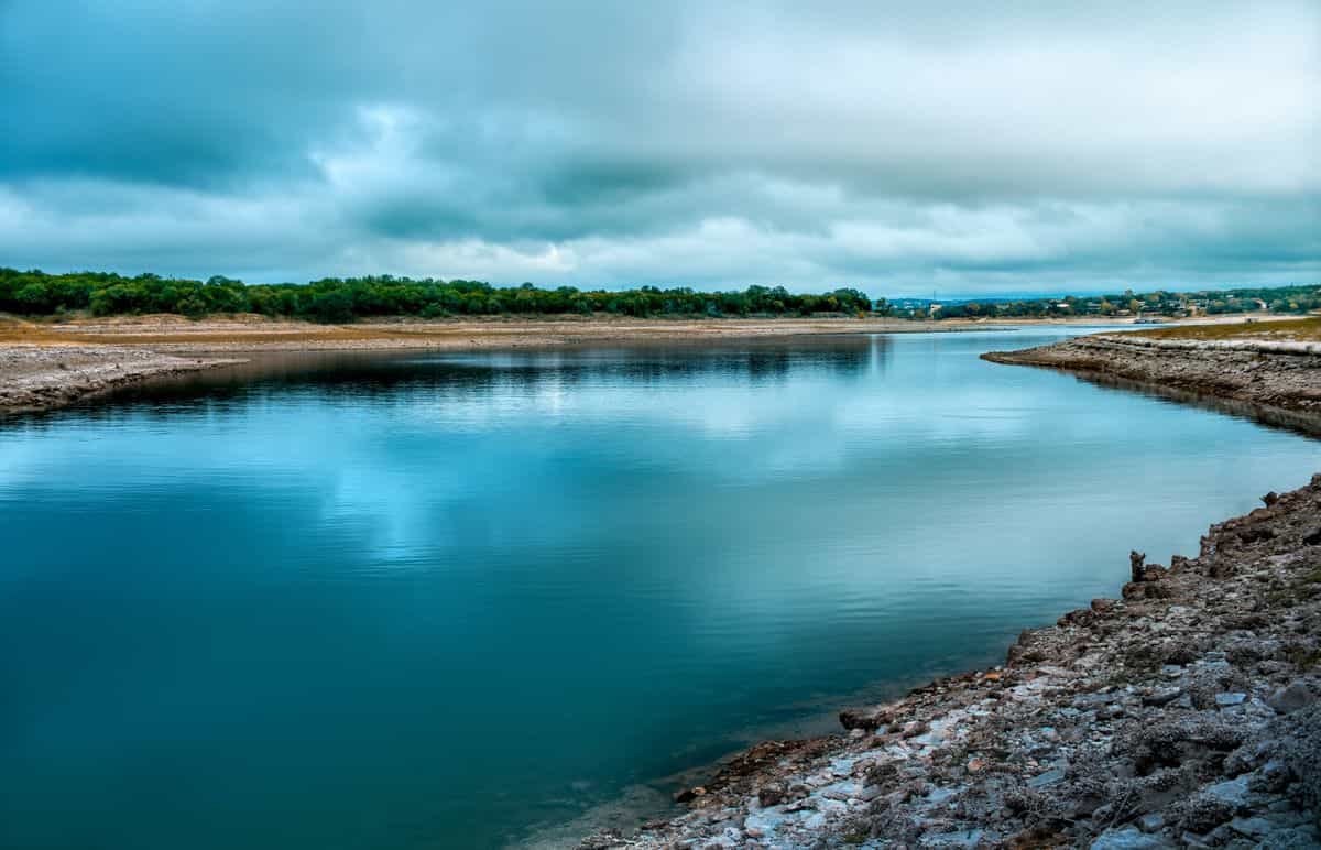 A calm Central Texas river under a cloudy sky