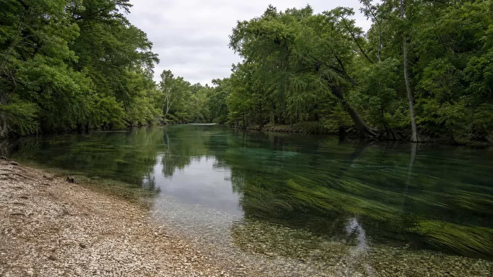 Older riverside homes with deep porches set back from the slow, clear San Marcos River at Martindale