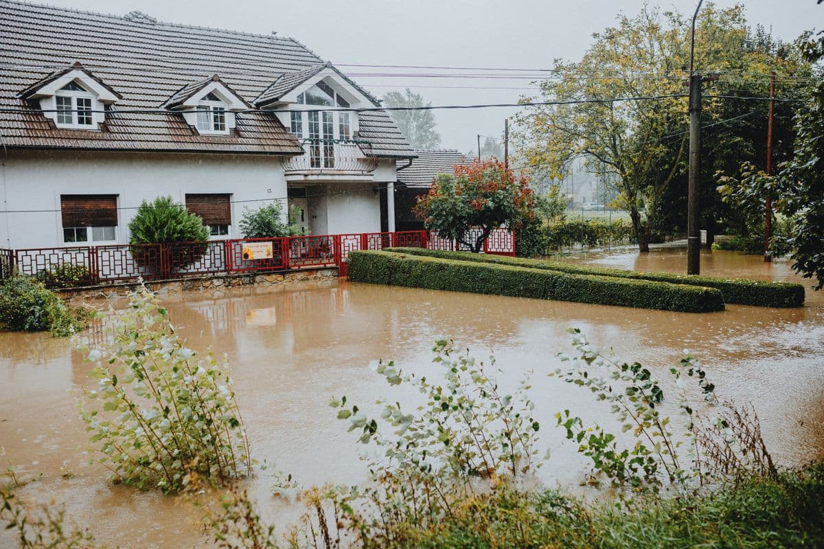 A Central Texas home the day after floodwater receded, with a mud line on the siding and removed materials at the kerb