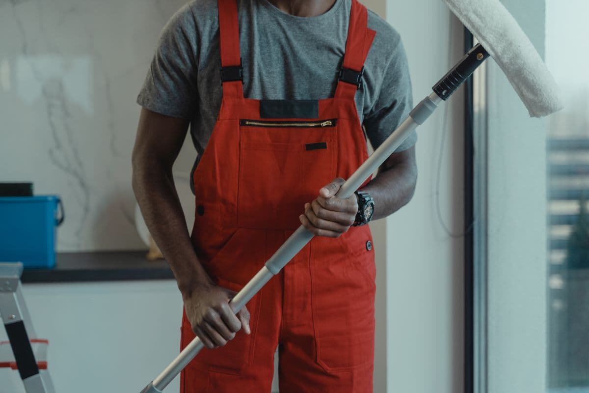 A technician in protective coveralls removing sealed disposal bags from a stripped bathroom