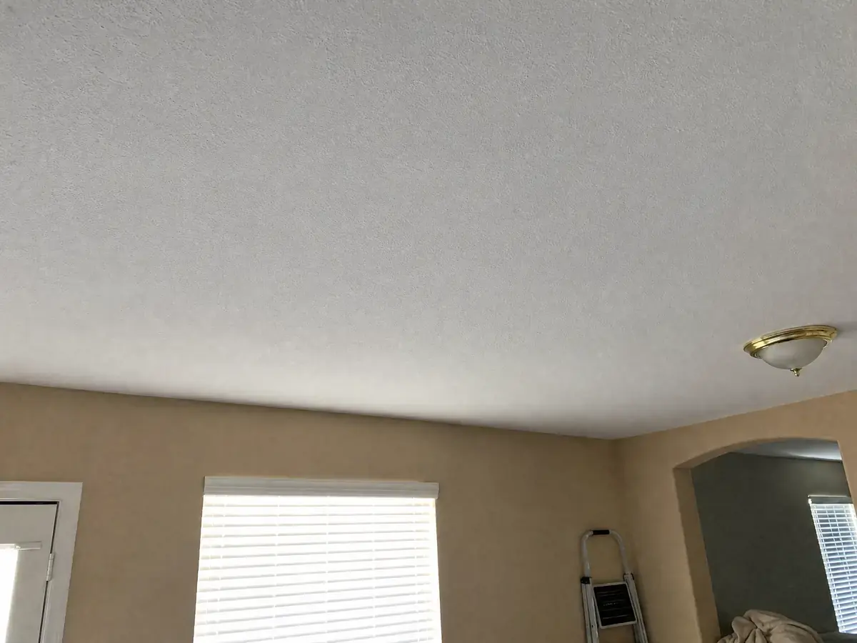 The same ceiling repaired with new drywall, textured to match and painted clean white, flat and uniform with no stain or sag.