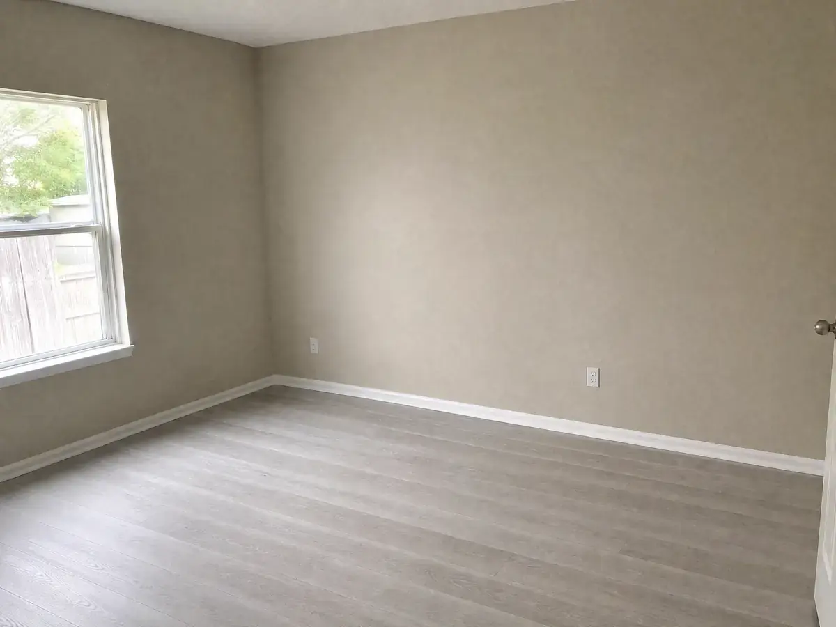 The same bedroom finished: new drywall taped, textured and painted, new baseboard installed and new vinyl plank flooring laid throughout.